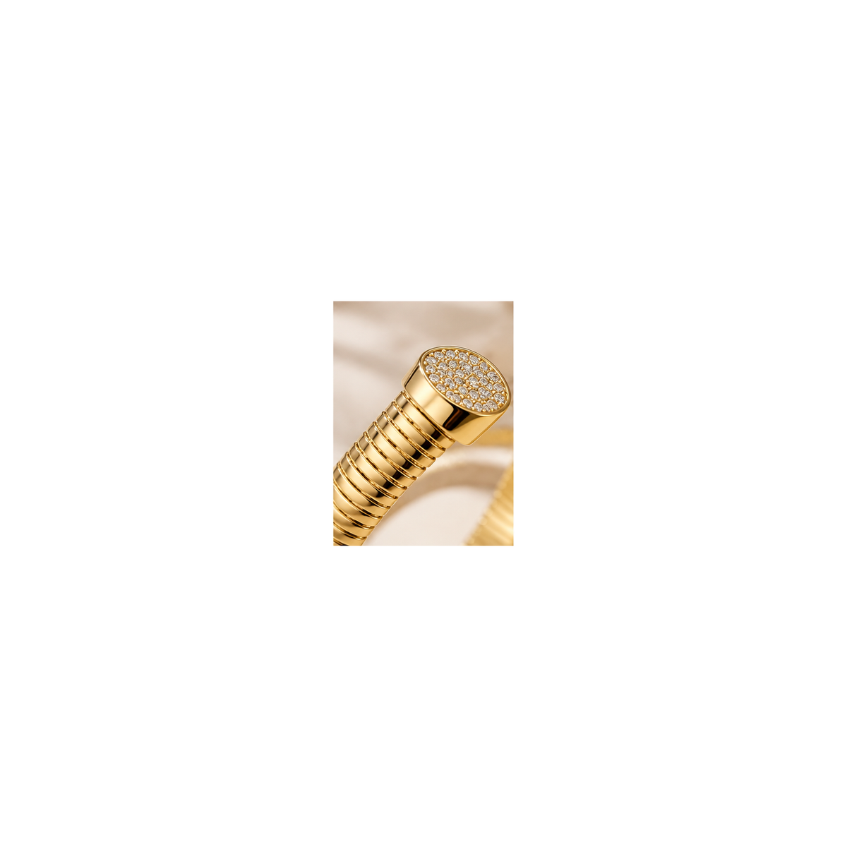 Close-up of ribbed gold-tone bracelet and pavé-style end cap